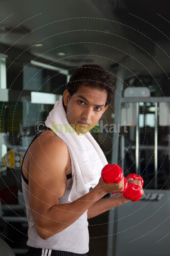 close-up portrait of a man holding red dumbbells at the gym