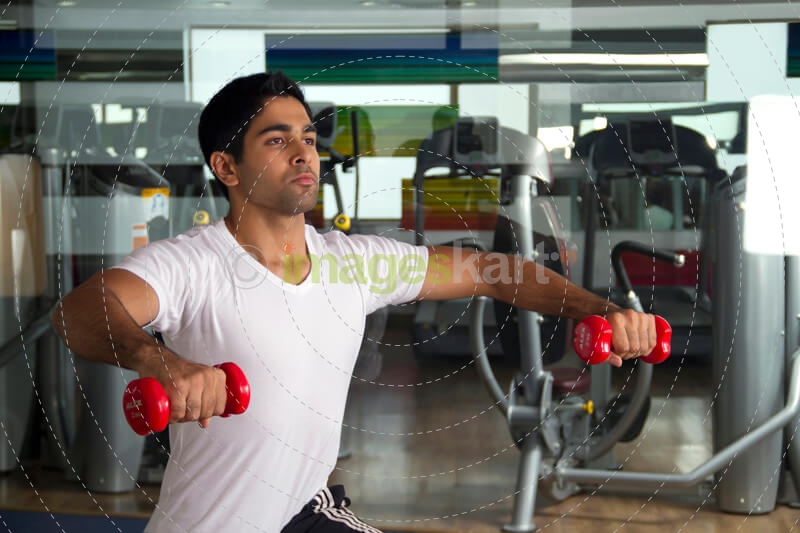 young man lifting light red dumbbells
