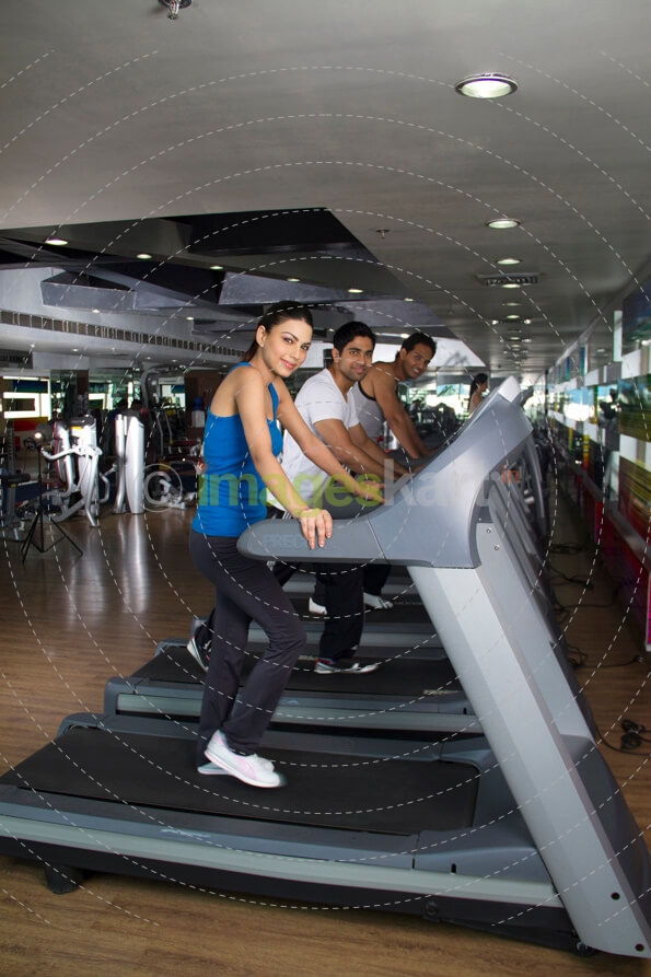 attractive female in blue tank top standing on a treadmill 