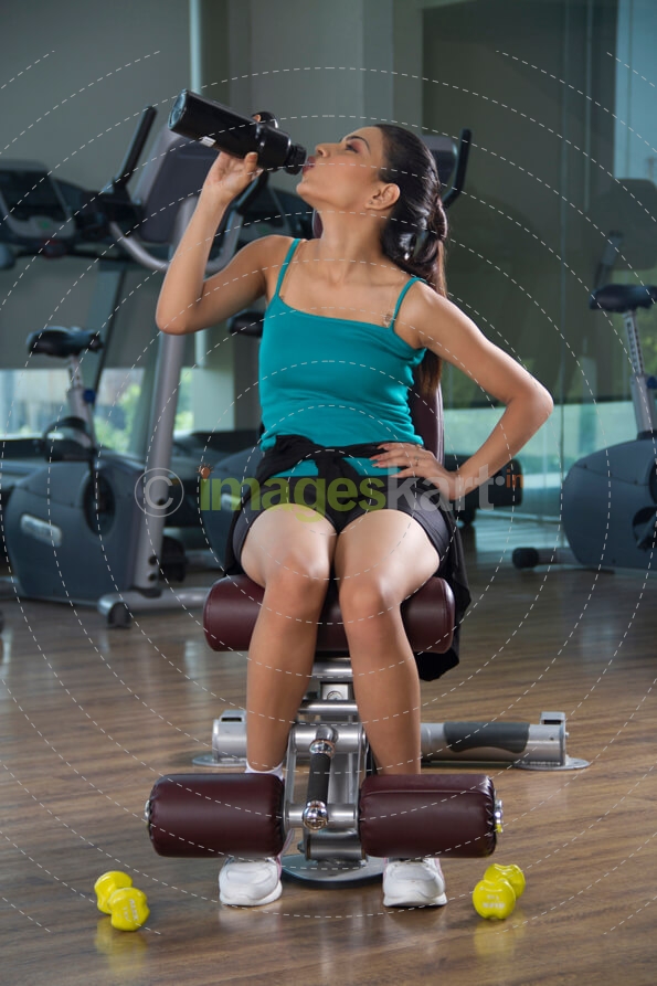 woman drinking water after doing her dumbbells