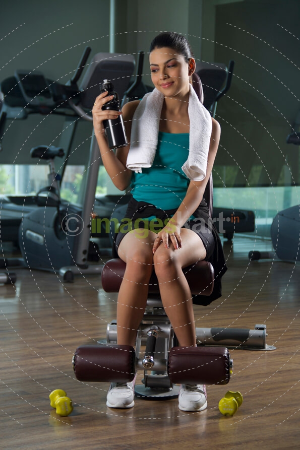 teenager in gym wear posing with a black coloured water bottle