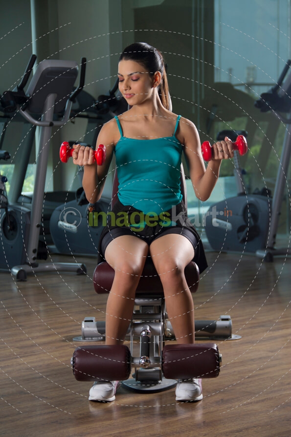 attractive female exercising with red dumbbells