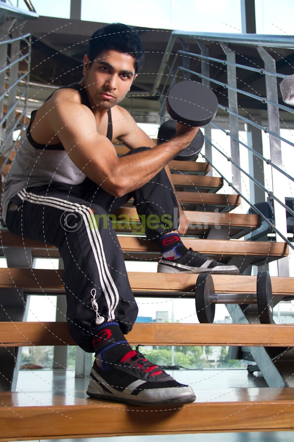 boy sitting at the stairs holding dumbles