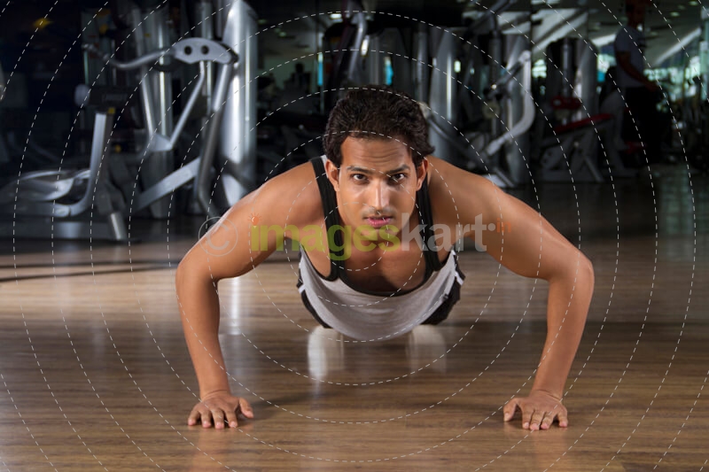young teenager in a vest doing push ups on the floor
