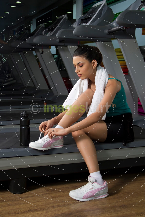 young girl tying her shoe lace at the gym