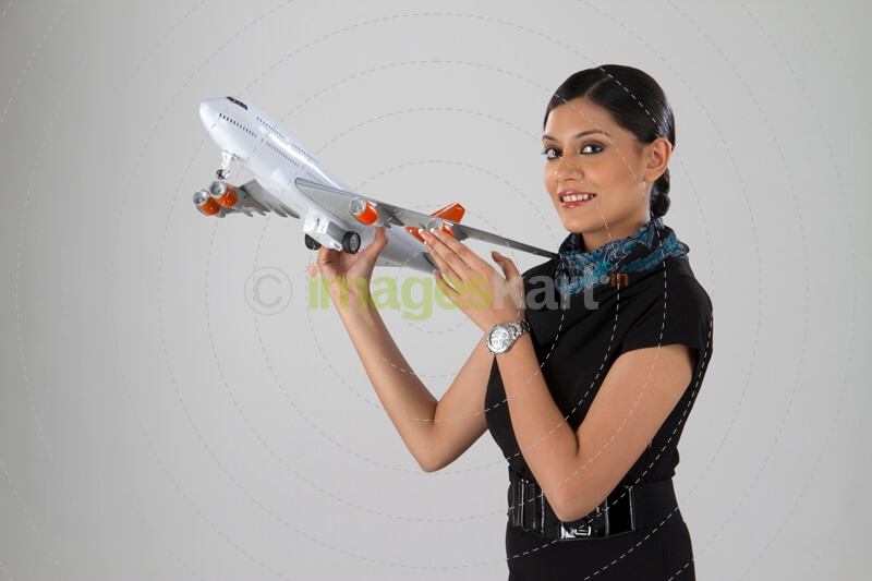airhostess smiling and posing with an airplane