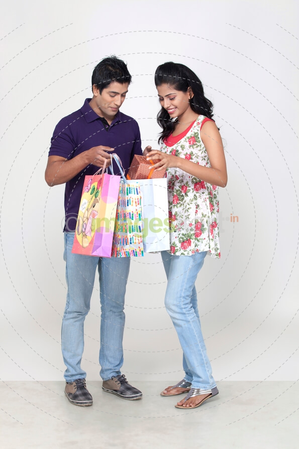 couple standing and peeking at shopping bags 