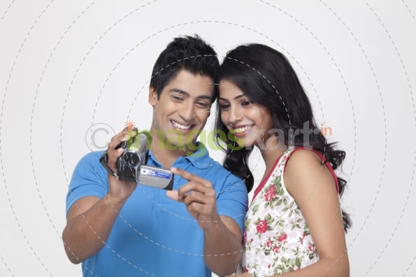 couple smiling while recording something with video camera 