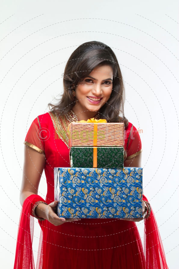 woman in ethnic wear posing for the camera holding gifts 