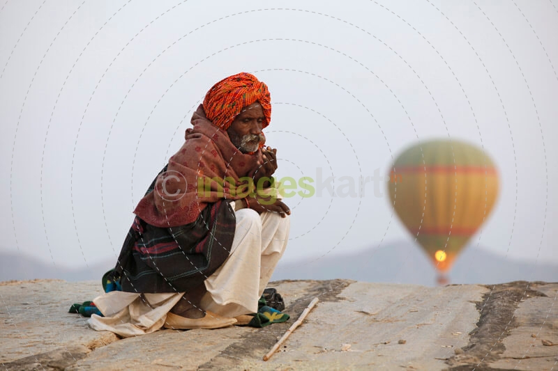 rural man sitting with hot air balloon in background 