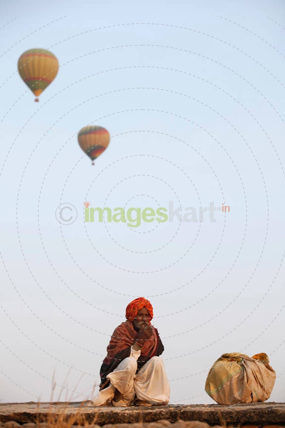 rural man sitting with hot air balloons in background 