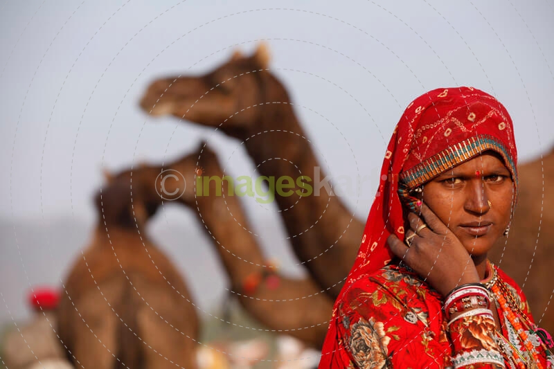 village woman standing against the background of camels