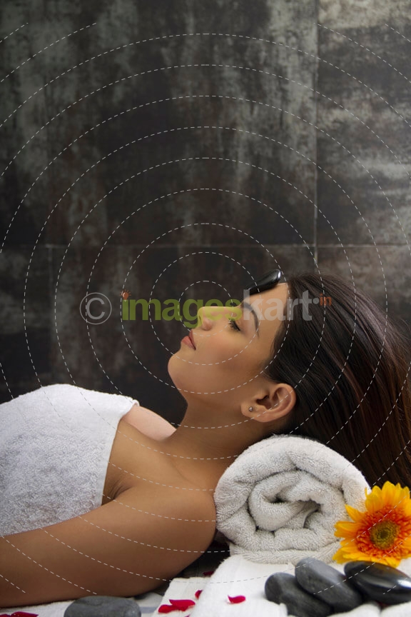 girl lying down at spa center for hot stone massage 