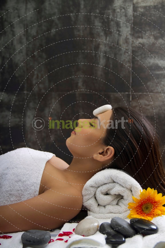 close up of a girl lying with hot stone on forehead 
