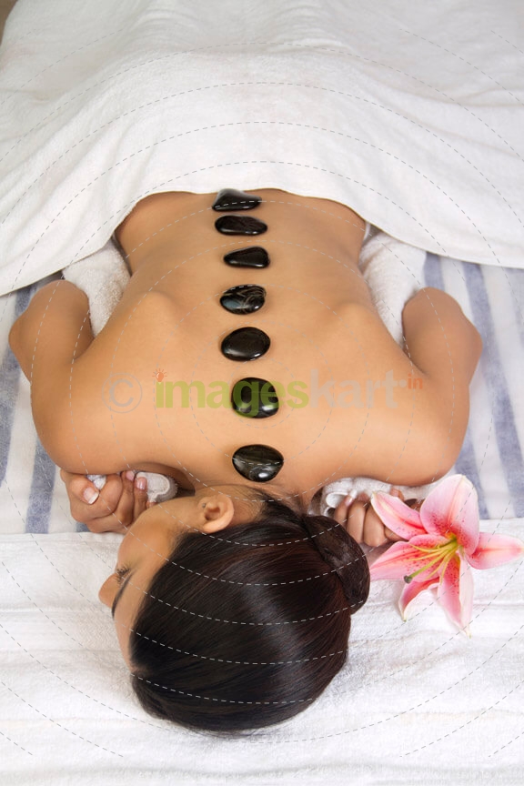 girl lying down with hot stone at the back