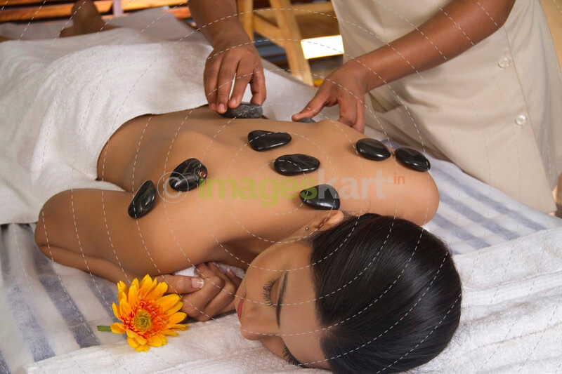 girl having back hot stone massage treatment at spa