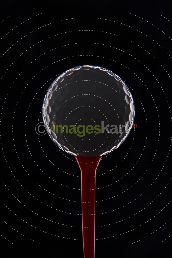 golf ball on golf tee against dark background 