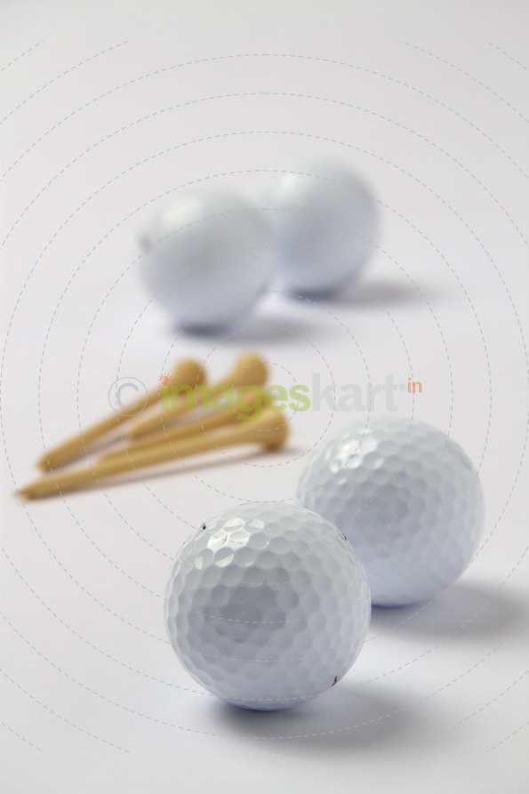 four golf balls with golf tees on white surface 