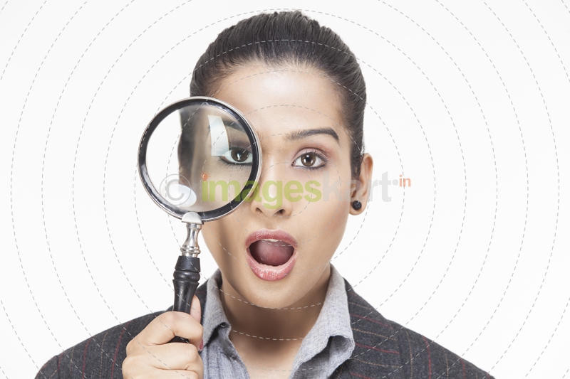girl shocked while looking at the camera holding magnifying glass