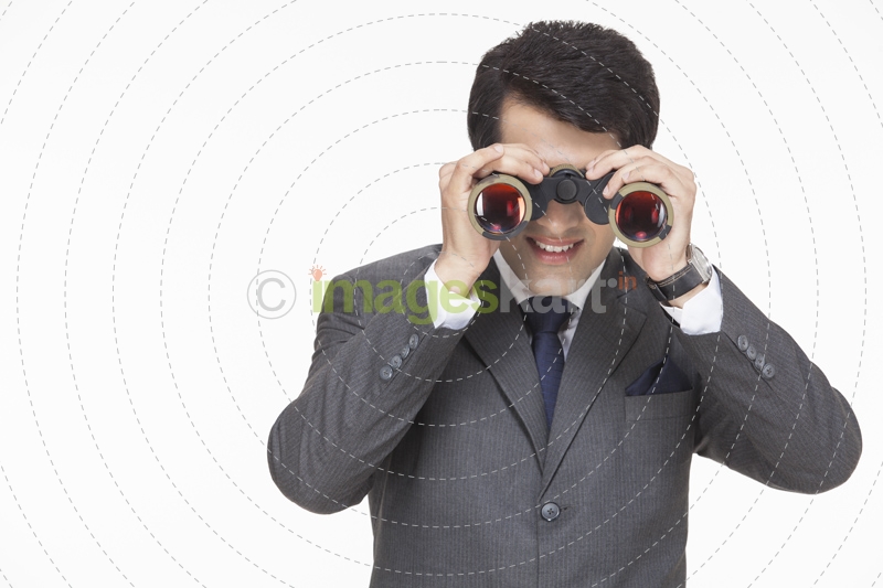young businessman looking for something through binoculars 