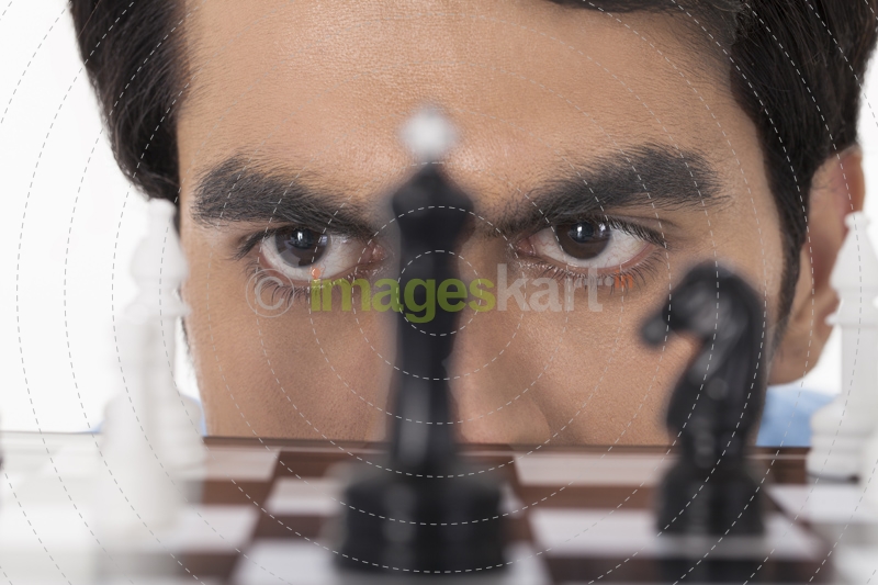 man thinking while looking at chess pawns 