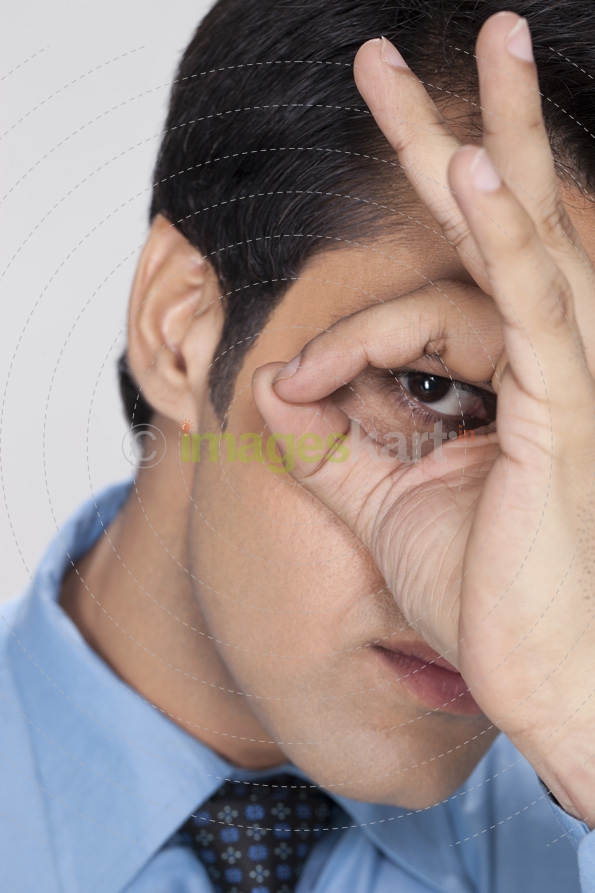 young businessman looking at the camera through hand hole 