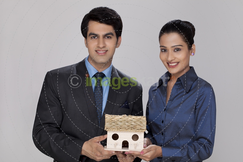couple holding home miniature looking at the camera