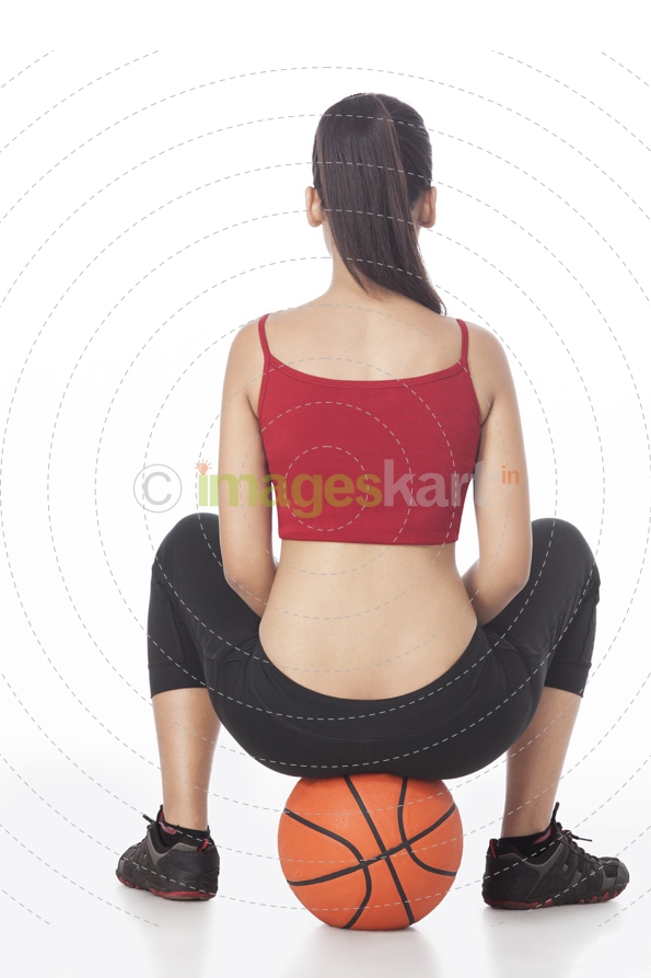 back view of girl sitting on basketball
