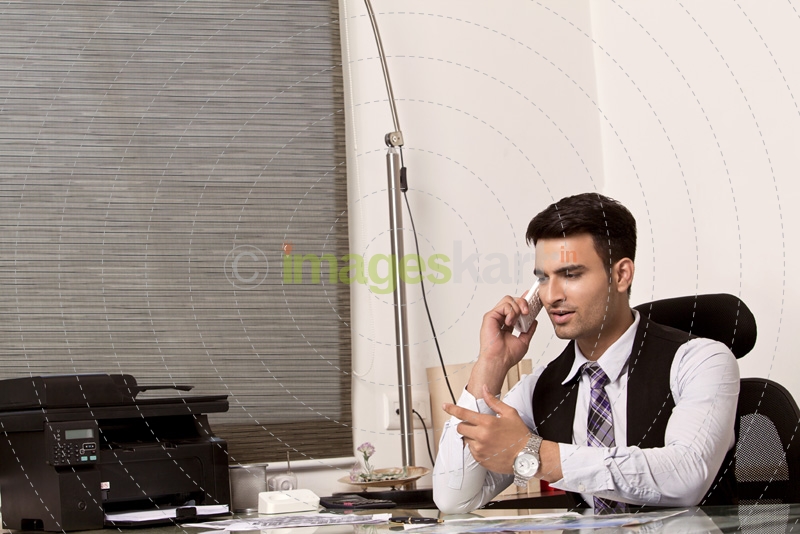 man at his office desk and talking on phone 