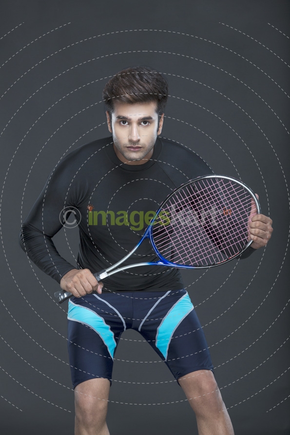 man looking at camera holding tennis racket 