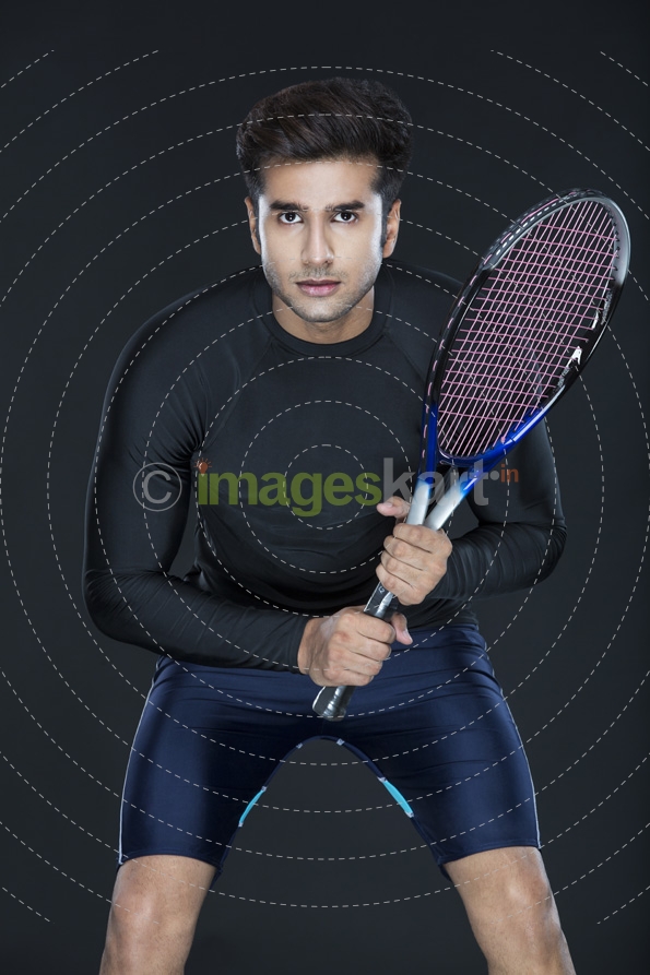 man looking at the camera while holding a tennis racket 