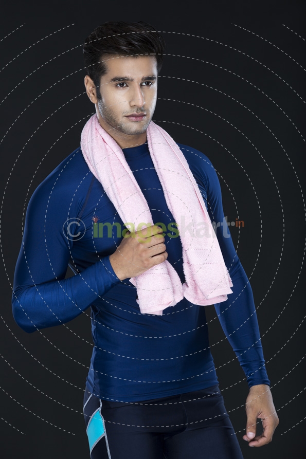 man posing in gym wear holding towel 