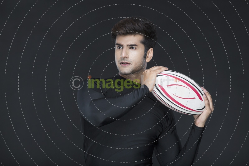 man holding rugby ball while posing for the camera 