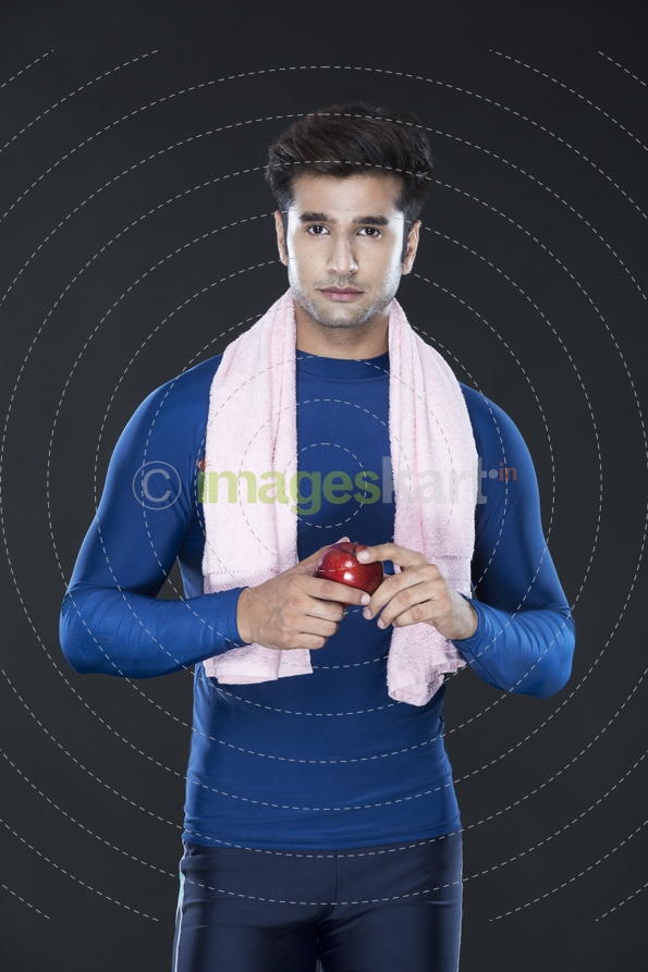 guy in gym wear carrying towel and posing with an apple 