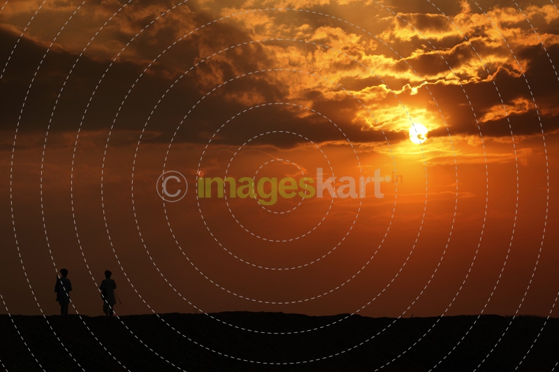 silhouette of two men standing against sun