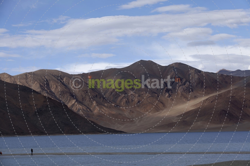 man standing on a river bank against a beautiful mountain view
