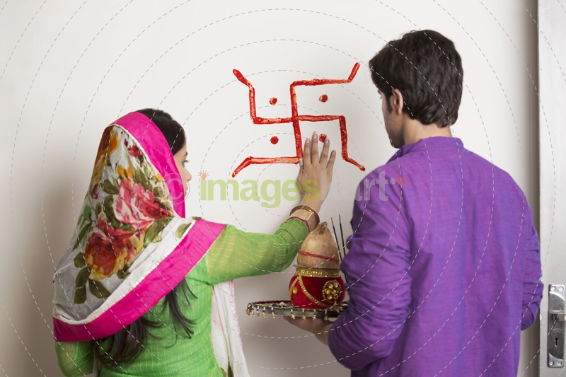 couple making swasthik in their new home 