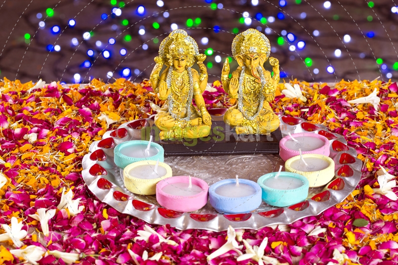 lord ganesha and luxmi statues with diyas in front