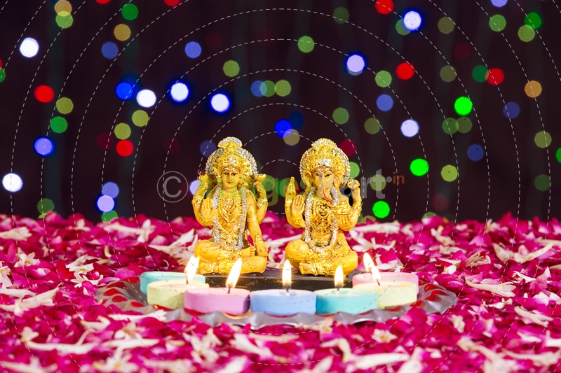lord ganesha and luxmi statues with diyas in front