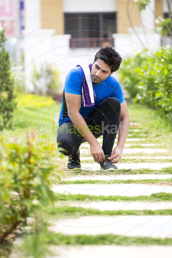man on jogging track and tying his shoe laces 