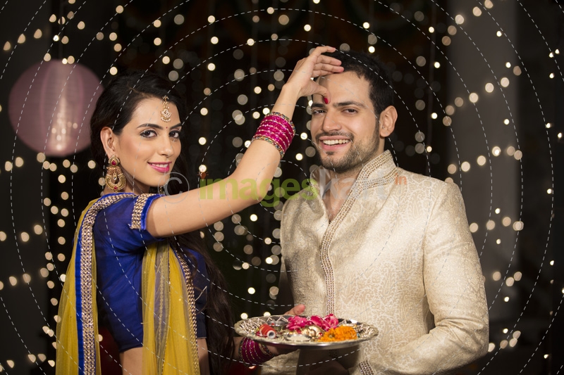 couple celebrating diwali and wife applying tika to husband 