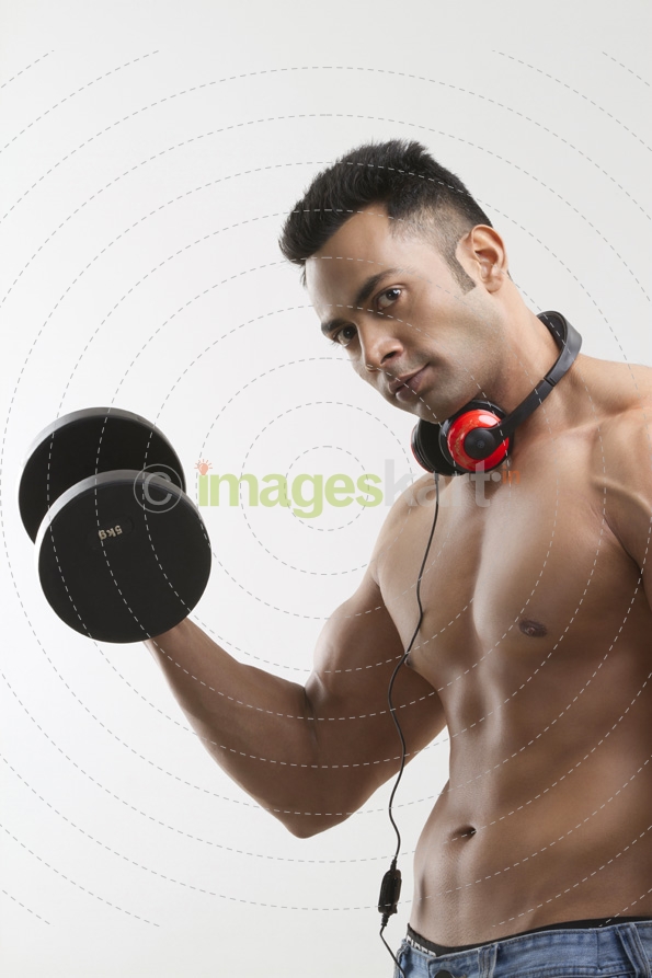 man posing with dumbbells and headphones
