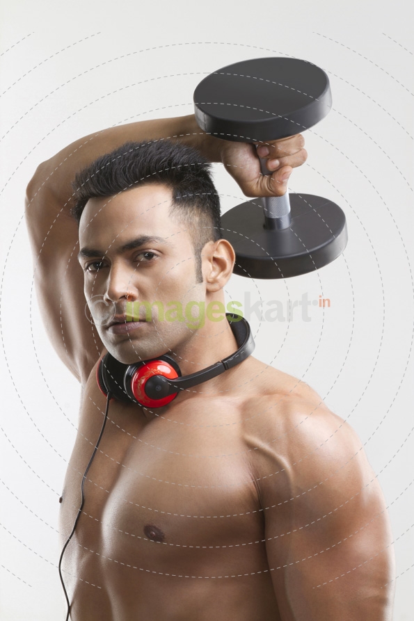 man posing with dumbbells and headphones