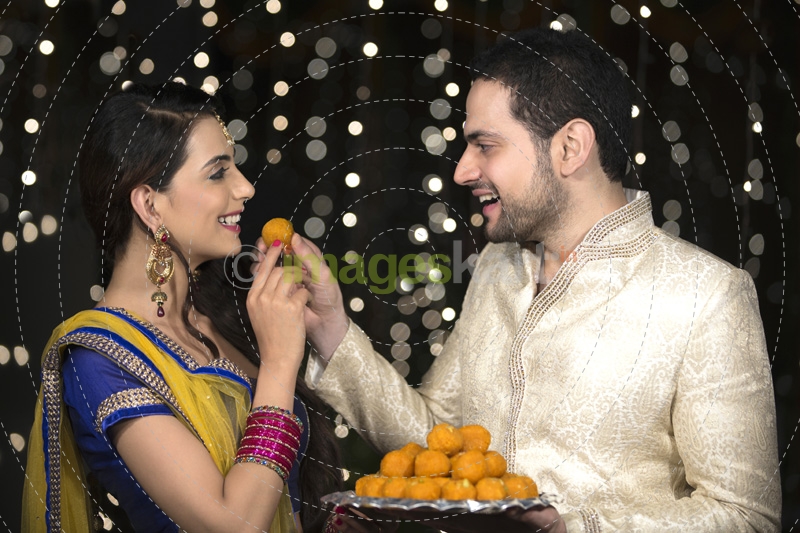 husband feeding ladoo to wife 