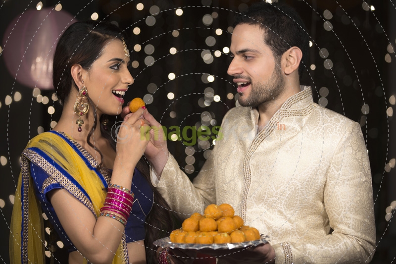 husband feeding ladoo to wife 