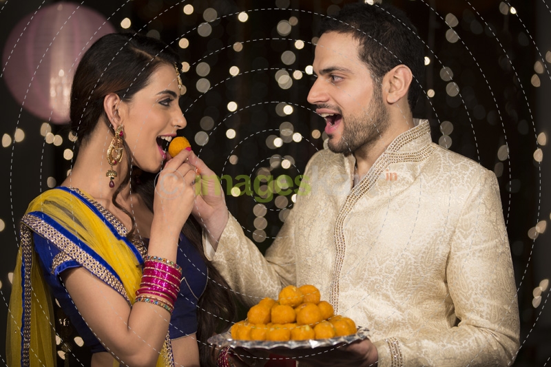 husband feeding ladoo to wife 