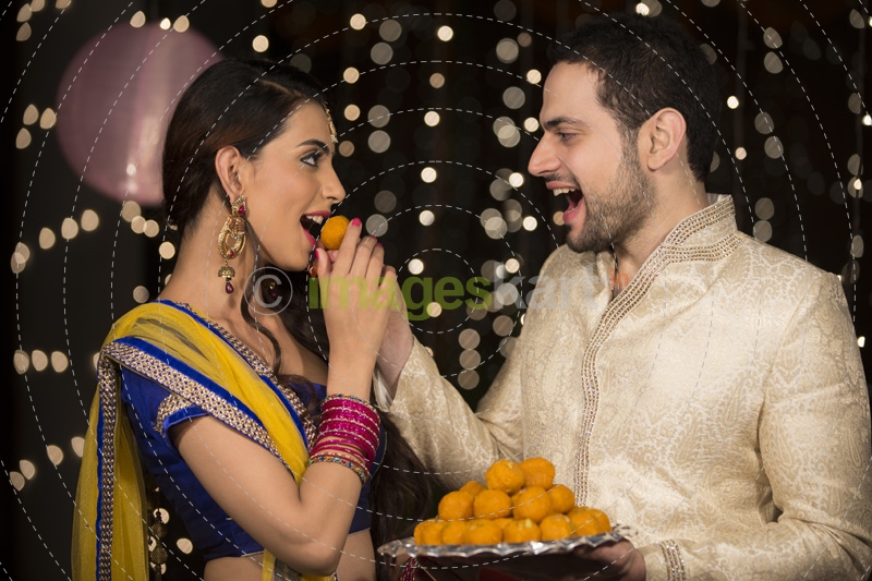 husband feeding ladoo to wife 