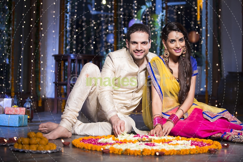 couple sitting and making rangoli on diwali