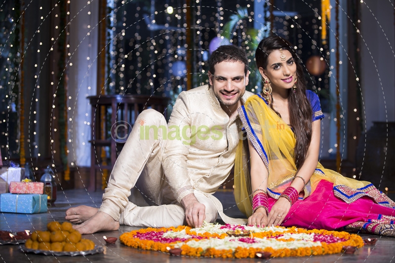 couple sitting and making rangoli on diwali