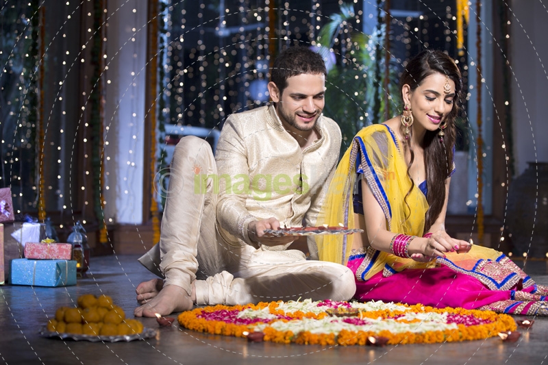 couple sitting and making rangoli on diwali